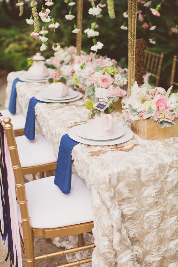 A pretty garden bridal shower table with a fabric flower tablecloth, pretty neutral and pastel florals, fresh blooms hanging from above