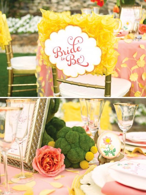 a bright garden bridal shower tablescape with moss balls, craspedia, embroidered blooms, a pink tablecloth with yellow petals