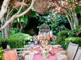 a bright garden shower tablescape with a pink runner, coral and orange napkins, bright blooms, a cage and a vine sphere over the table