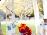 a simple garden bridal shower tablescape with bold florals in blue vases and bold blooms on each place setting plus paper flowers over the table