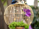 a decorative round cage with moss and paper butterflies for accenting a garden bridal shower space