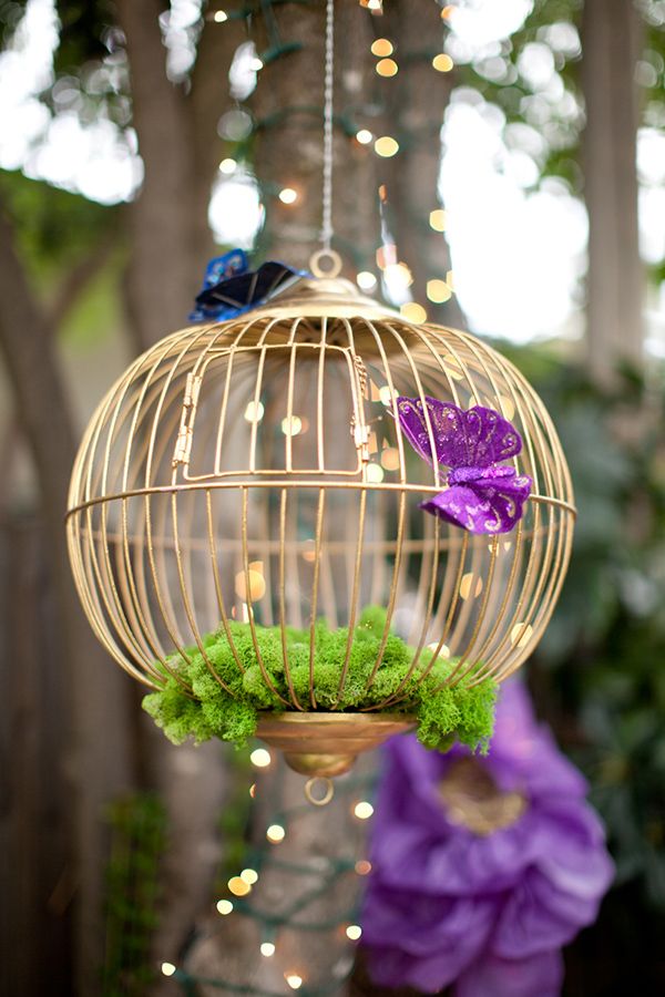 A decorative round cage with moss and paper butterflies for accenting a garden bridal shower space