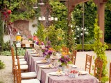 a bright garden bridal shower tablescape with a pink printed tablecloth, bright blooms and climbing plants covering the pillars