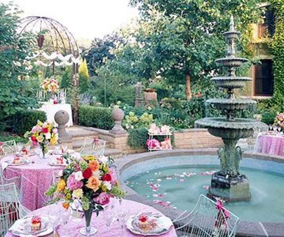 A refined vintage garden bridal shower space with pink tablescapes, bright blooms, petals in the fountain and chic chairs