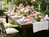 a bright spring bridal shower table with pink blooms, greenery, colored glasses and chargers