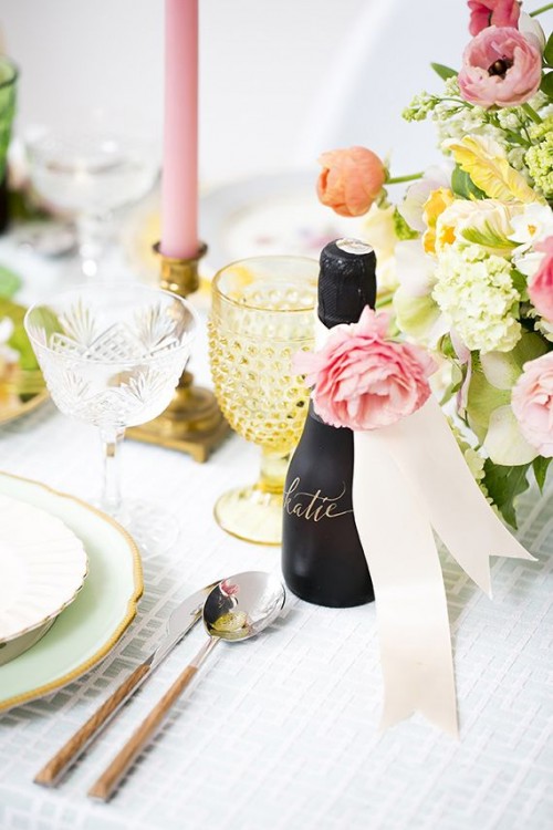 a soft pastel spring bridal shower table with bright blooms, candles and glasses and gold rim plates