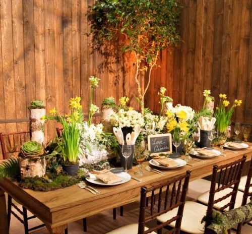a woodland bridal shower table with succulents, greenery, blooming bulbs, moss and chalkboard signs