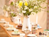 a spring tea party bridal shower table with vintage floral teacups and lush floral centerpieces