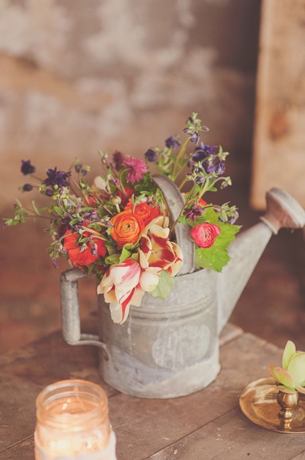 a simple bridal shower centerpiece of a vintage watering can and colorful blooms for decor