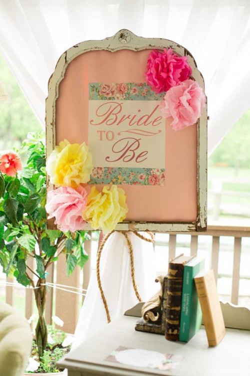 vintage books and a vintage memo board with bright paper flowers and signs and greeenery is simple and lovely decor for a vintage bridal shower