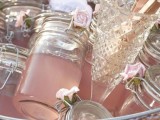 a silver bucket with jars with pink jelly and pink blooms is a lovely idea for a refined vintage bridal shower