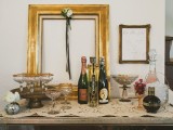 a small and chic drink table for a vintage bridal shower, with champagne and gold-rimmed glasses plus blooms in round vases