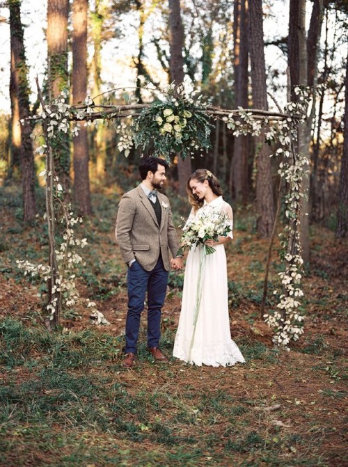 a lightweight woodland wedding arch of branches, with greenery, foliage and white blooms for a spring woodland wedding