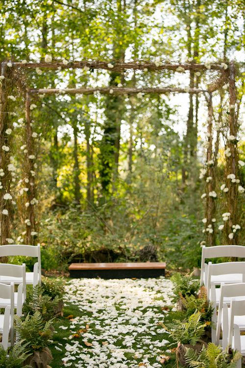 an ethereal woodland wedding arch of branches and twigs, with some greenery and white blooms for a spring wedding
