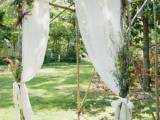 a wild woodland wedding arch of branches and sticks, with wildflowers, white curtains and bows is an amazing idea for a woodland wedding