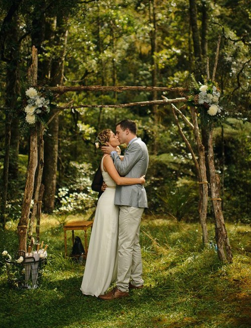 a woodland wedding arch of branches with greenery and neutral blooms is a romantic and simple idea for a spring or summer woodland wedding