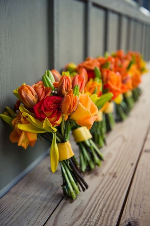 bold wedding bouquets of orange and red blooms, with yellow ribbons are amazing for an orange beach wedding