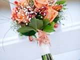 an orange bloom wedding bouquet with baby’s breath and leaves plus a white wrap is a cool idea for an orange beach wedding