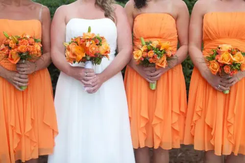 orange strapless A-line bridesmaid dresses with ruffles and draped bodices and orange wedding bouquets are amazing