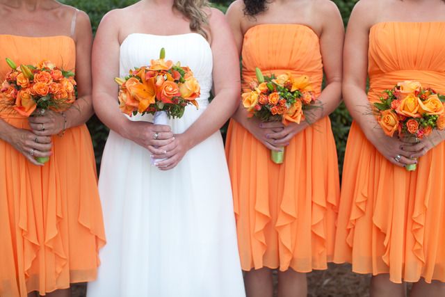 Orange strapless A line bridesmaid dresses with ruffles and draped bodices and orange wedding bouquets are amazing