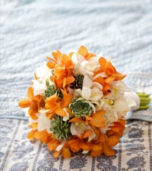 a bold wedding bouquet of orange and white blooms, with succulents and a white wrap is a gorgeous idea for an orange wedding