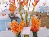 a bright orange bloom wedding centerpiece is a great idea for a colorful beach wedding, use tropical blooms for a more spectacular look