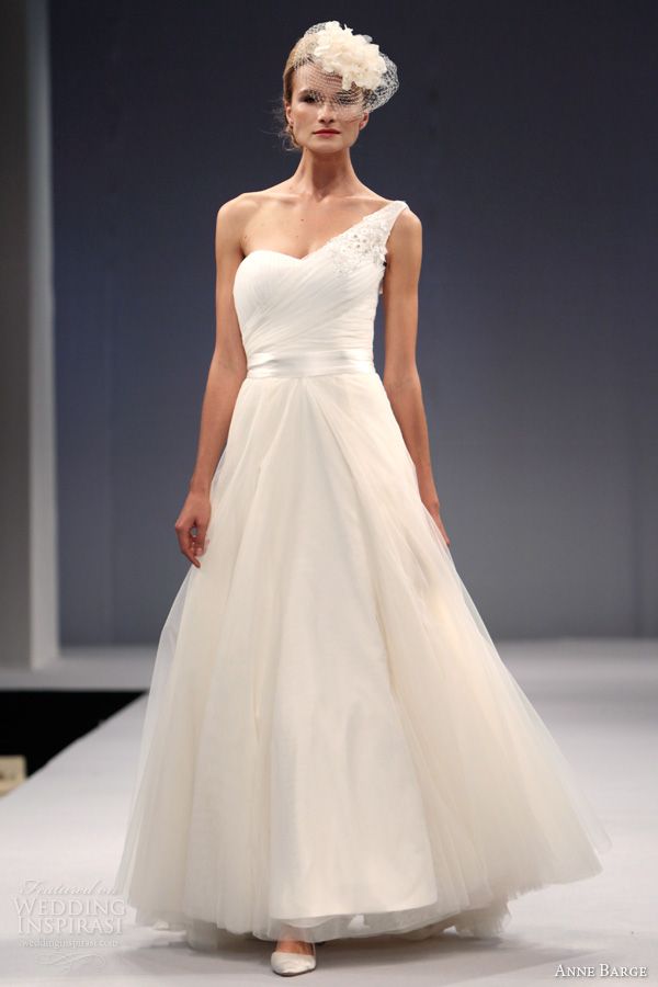 A modern one shoulder wedding ballgown a draped bodice, fabric blooms and a pleated skirt plus a matchign headpiece for a modern take on vintage look