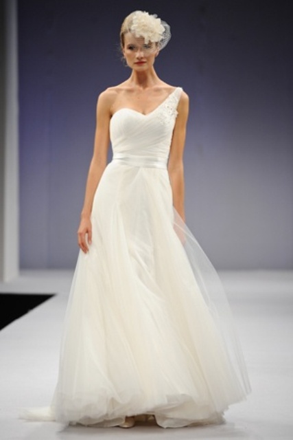 a modern wedding ballgown with a one shoulder neckline, a layered skirt and a small hat with fabric blooms for a refined look