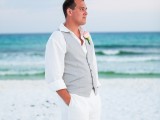 white pants, a white shirt, a light grey vest and a floral boutonniere for a relaxed beach outfit