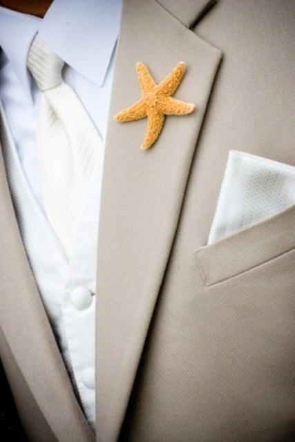 a formal beach groom's outfit with a tan suit, a white waistcoat, a white tie and a little star fish boutonniere