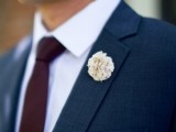 a formal groom’s outfit with a navy suit, a white shirt and a plum-colored tie