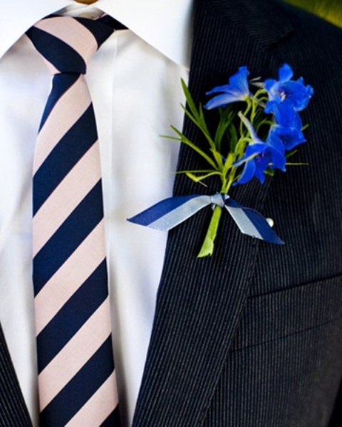 a black suit, a white shirt, a striped tie and a bright floral boutonniere to stand out with colors