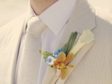 a creamy suit and a matching tie are refreshed with a bright floral boutonniere