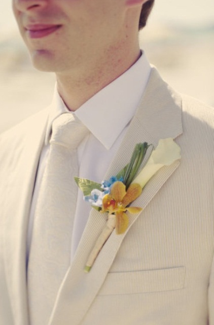 a creamy suit and a matching tie are refreshed with a bright floral boutonniere
