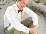 tan pants, tan suspenders, a white shirt and a red bow is a chic and bright beach groom look