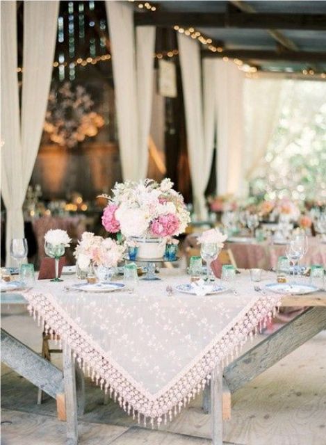 a refined vintage outdoor barn reception space with lovely textiles and white and pink floral arrangements