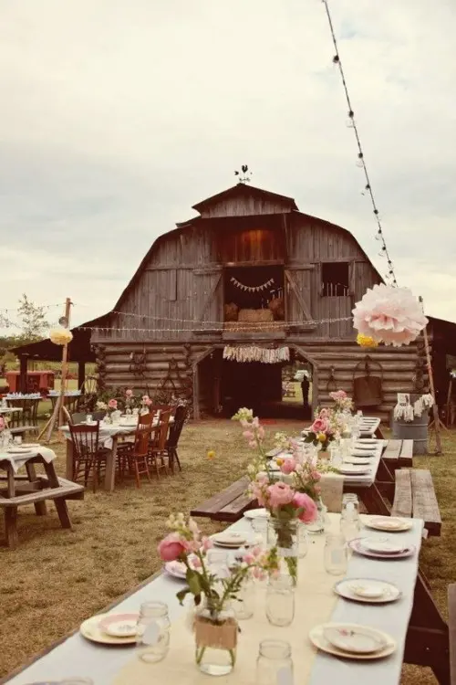 a cool outdoor barn wedding reception space with pink floral arrangements, neutral textiles and neutral porcelain is very cool and chic