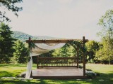 an outdoor wedding gazebo with neutral fabric and greenery is a lovely idea for an outdoor barn wedding or another rustic one