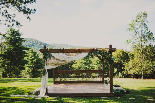 an outdoor wedding gazebo with neutral fabric and greenery is a lovely idea for an outdoor barn wedding or another rustic one