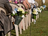 buckets with bold floral arrrangements are great to line up the aisle of an outdoor barn wedding reception