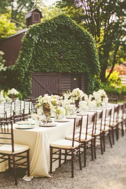 a refined white outdoor barn wedding reception space with white florals and white textiles plus elegant chairs is cool