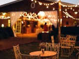 a cozy outdoor barn cocktail space with string lights and chairs and tables is a lovely idea