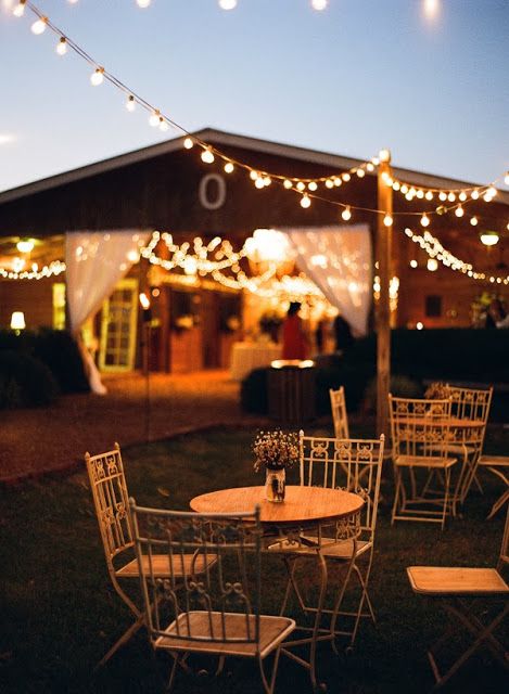 a cozy outdoor barn cocktail space with string lights and chairs and tables is a lovely idea