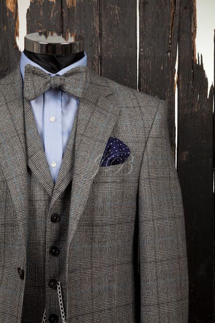a grey tweed three-piece suit with a matching bow tie and a blue shirt plus a navy handkerchief