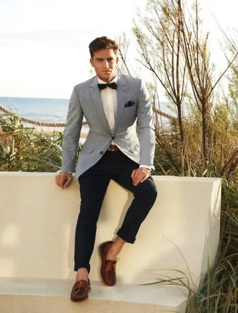 a catchy nautical groom's look with black pants, a white button down, a black bow tie, a blue thin striped blazer and brown loafers