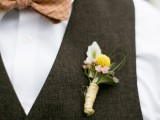 a stylish groom’s look with a white button down, a chocolate brown waistcoat and a rust bow tie plus a floral boutonniere