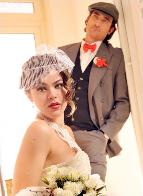 a vintage groom's outfit with a taupe suit, a graphite grey waistcoat, a white button down, a red bow tie and a cap