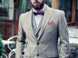 a vintage groom’s look with a grey checked suit, a grey waistcoat, a burgundy printed bow tie and a hat