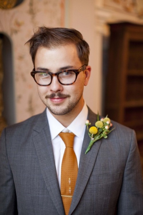 a vintage groom's look with a grey suit, a white button down and a rust tie plus a billy ball boutonniere