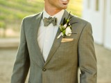 a vintage-inspired groom’s look with a light grey suit, a white button down and a printed bow tie plus a florla boutonniere